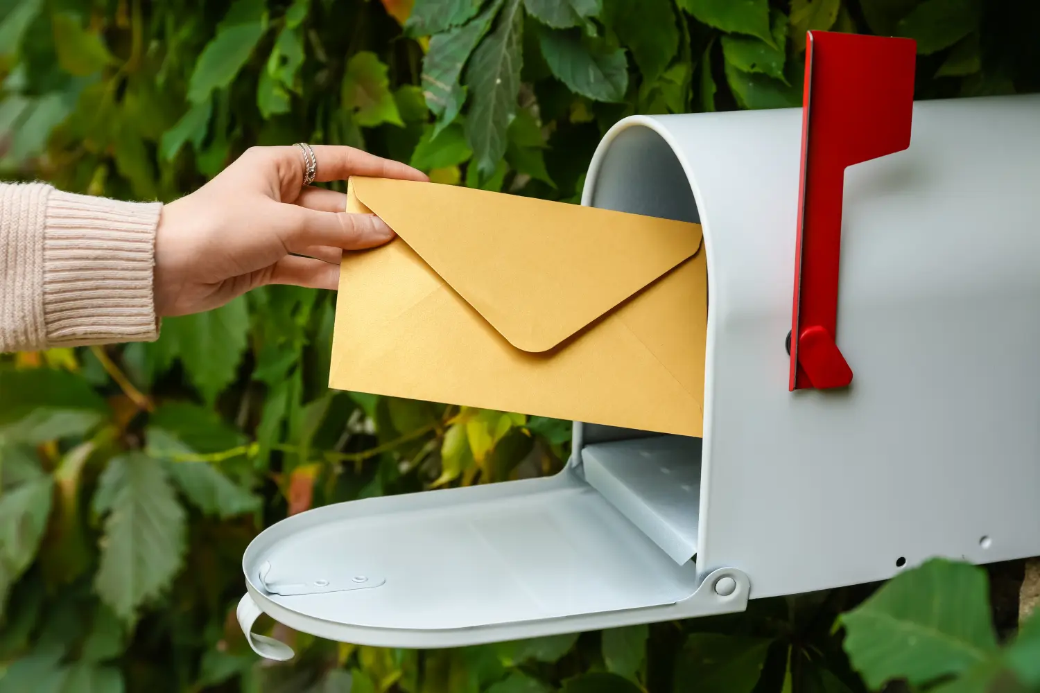 Frau bekommt draußen Brief aus Briefkasten, Nahaufnahme